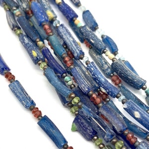 Peut inclure: Un brin de perles en verre bleu avec un aspect mouchet&eacute; et nuageux. Les perles sont entrecoup&eacute;es de perles plus petites, rouges, vertes et bleues.