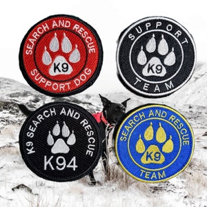 May include: Four embroidered patches featuring a paw print design. The patches are black, red, blue, and yellow. The text on the patches reads "Search and Rescue", "Support Dog", "K9 Team", and "K94".