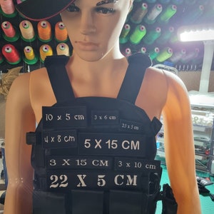 May include: Black tactical vest with multiple white velcro patches, each with different measurements in centimetres. The patches include: 10 x 5 cm, 3 x 6 cm, 2.5 x 5 cm, 4 x 8 cm, 5 x 15 cm, 3 x 15 cm, 3 x 10 cm, and 22 x 5 cm.