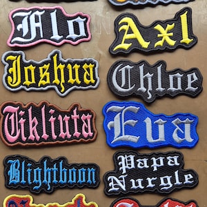 May include: A collection of ten embroidered name patches featuring gothic-style lettering. The patches display various names and words including Francesca, Tutt's, Flo, Axl, Joshua, Chloe, Tikliuta, Eva, Blightboon, Papa Nurgle, Nurgle, and Split in colours.