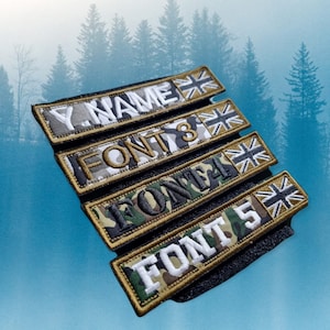 May include: Five different camouflage patterned dog tags with a gold trim and a white Union Jack flag. The tags are labelled "Y. Name", "FONT 3", "FONT 4", and "FONT 5".