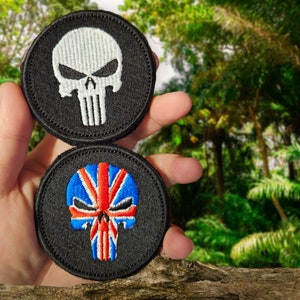 May include: Two black embroidered patches with skull designs. One skull is white with a black outline, the other is red, white, and blue with a Union Jack design.