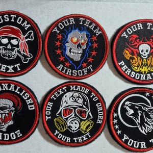 May include: Six embroidered patches with various designs, including skulls, flames, a gas mask, and a wolf. Each patch has a black background with red stitching and white embroidery. The patches have text that says "Custom Text", "Your Team Airsoft", "Your Text Personalised", "Personalised Badge", "Your Text Made To Order", and "Your Text".