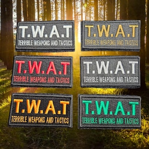 May include: Six black patches with the text "T.W.A.T. TERRIBLE WEAPONS AND TACTICS" in different coloured thread. The colours are white, gold, red, grey, orange, and green.