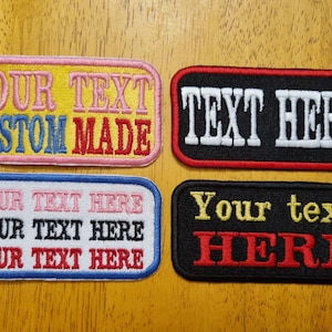May include: Four embroidered iron-on patches with different colour combinations and text. The first patch is yellow with pink, blue, and red text that reads "YOUR TEXT CUSTOM MADE". The second patch is black with red text that reads "TEXT HERE". The third patch is white with blue, pink, and black text that reads "YOUR TEXT HERE YOUR TEXT HERE YOUR TEXT HERE". The fourth patch is black with gold and red text that reads "Your text HERE".