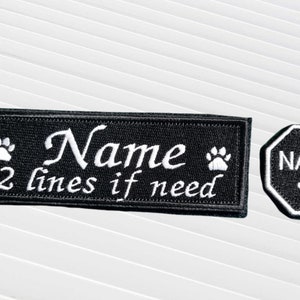 May include: Two black embroidered patches for a dog collar. One patch is rectangular and says "Name 2 lines if need" with a paw print on each side. The other patch is an octagon and says "NAME" with a paw print in the centre.