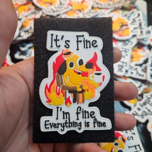 May include: A rectangular sticker with the words "It's Fine" and an illustration of a yellow dog in a burning room, holding a coffee cup. The text "I'm fine, Everything is fine" is also included on the sticker.
