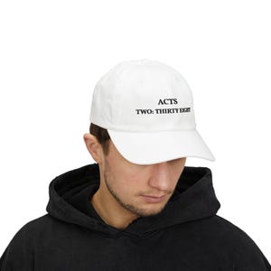 Op de afbeelding: Witte baseballpet met de tekst "ACTS TWO: THIRTY EIGHT" in zwart. De pet is gemaakt van een zacht materiaal en heeft een gebogen klep. Een klassieke stijl, geschikt voor dagelijks gebruik.