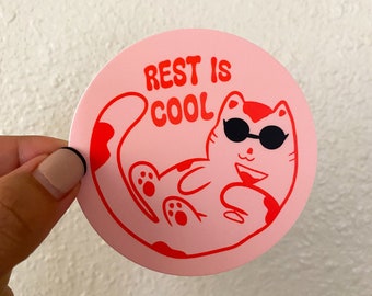 May include: Pink round sticker with a red cartoon cat wearing sunglasses and the text "REST IS COOL" in red.
