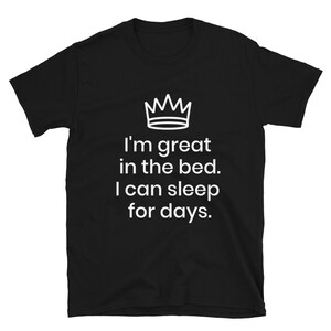 May include: Black t-shirt with white text that reads "I'm great in the bed. I can sleep for days." and a crown graphic above the text.