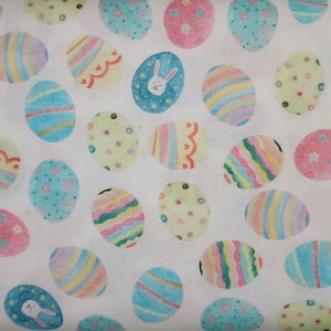 May include: White fabric with a repeating pattern of colorful Easter eggs. The eggs are decorated with stripes, dots, and swirls. Some eggs have a bunny face.