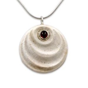 Pode incluir: Um pendente redondo, branco sujo, com um design em espiral e uma pequena pedra preciosa vermelha no centro. O pendente é suspenso por uma fina corrente prateada. A pedra preciosa está engastada em metal dourado.