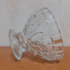 May include: A clear glass bowl with a decorative pattern. The bowl is tilted on its side, revealing the intricate design.