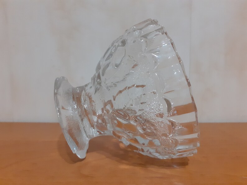 May include: A clear glass bowl with a decorative pattern. The bowl is tilted on its side, revealing the intricate design.