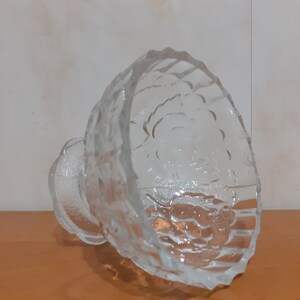 May include: A clear glass bowl with a textured surface. The bowl has a wide, round base and a deep, rounded bowl. The bowl is made of clear glass and has a textured surface.
