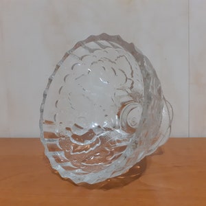 May include: A clear glass bowl with a textured design. The bowl has a wide, round base and a flared rim.