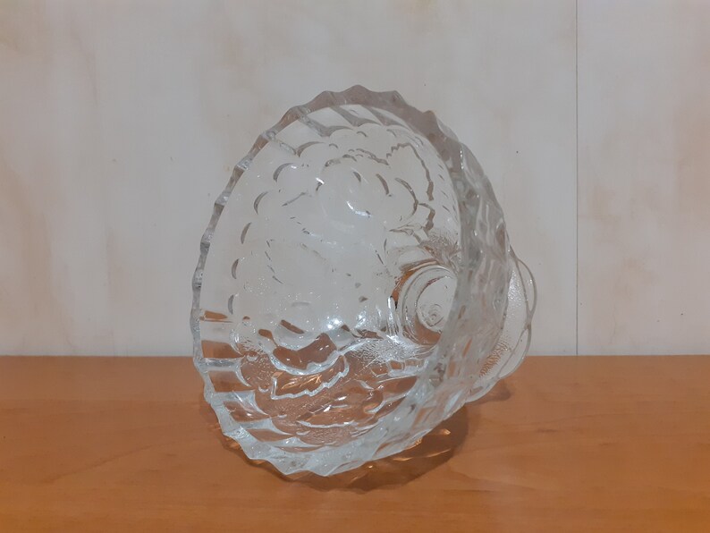 May include: A clear glass bowl with a textured design. The bowl has a wide, round base and a flared rim.