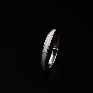 Op de afbeelding: Een dunne zilveren ring met een witte opaal inlay.