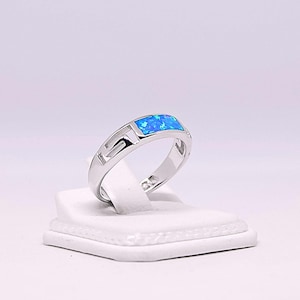 May include: A silver ring with a blue opal stone set in a geometric design.