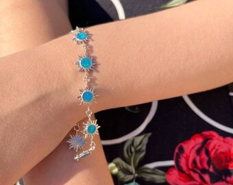Può includere: Un braccialetto d'argento con ciondoli a forma di sole blu turchese. Il braccialetto ha una chiusura a moschettone.