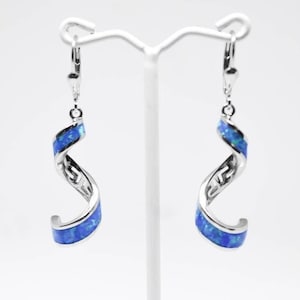 Peut inclure: Une paire de boucles d'oreilles pendantes en argent avec un motif en spirale d'opale bleue. Les boucles d'oreilles ont une fermeture à levier.