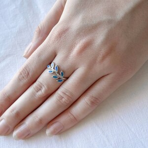 May include: A silver ring with a delicate branch design featuring blue opal stones.