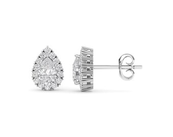 May include: A pair of silver pear-shaped earrings with a halo of smaller diamonds around the center stone.