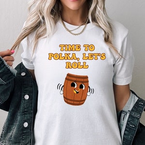 May include: White t-shirt with the text "Time to Polka, Let's Roll" and a cartoon barrel with a smiling face.