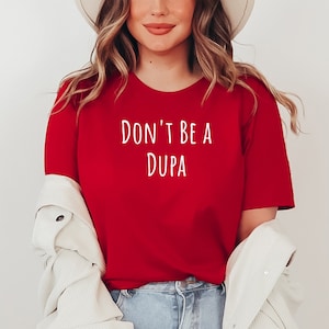 May include: A red t-shirt with the text "DON'T BE A DUPA" in white lettering.