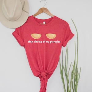 May include: Red t-shirt with a white graphic of two pierogies and the text "stop staring at my pierogies".