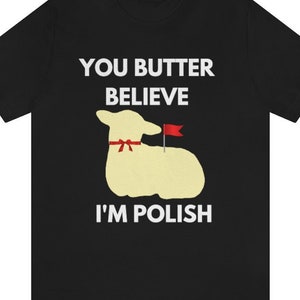 May include: Black t-shirt with white text that reads "You butter believe I'm Polish". A cartoon image of a yellow lamb with a red bow and a red flag is in the center of the shirt.