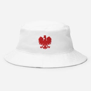 Puede incluir: Sombrero de pescador blanco con un águila polaca bordada en rojo.