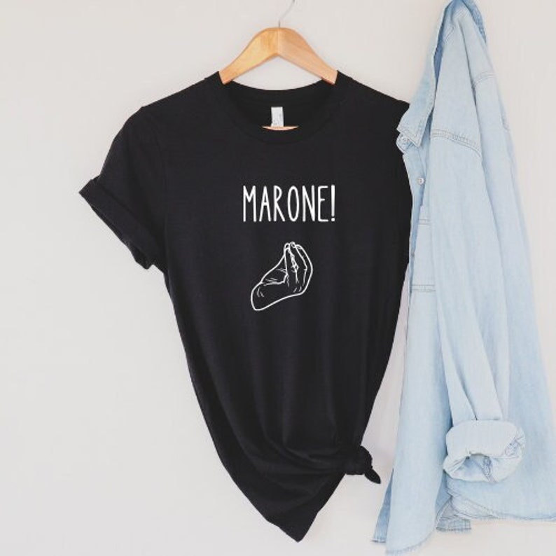 K&ouml;nnte beinhalten: Schwarzes T-Shirt mit wei&szlig;em Text "MARONE!" und einer wei&szlig;en Illustration einer Handgeste.