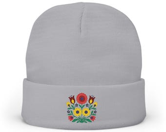 Puede incluir: Un gorro gris claro con un diseño de bordado floral colorido. Las flores bordadas incluyen elementos rojos, amarillos y verdes. El gorro es de un estilo clásico y cómodo.
