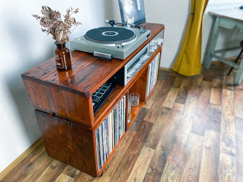 May include: A wooden record player stand with a turntable, amplifier, and shelves for vinyl records. The stand is made of reclaimed wood and has a rustic look.