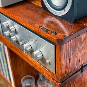 May include: A wooden shelf unit with a vintage Kenwood stereo receiver, a turntable, and a black speaker. The shelf has a dark wood stain and is made of reclaimed wood.