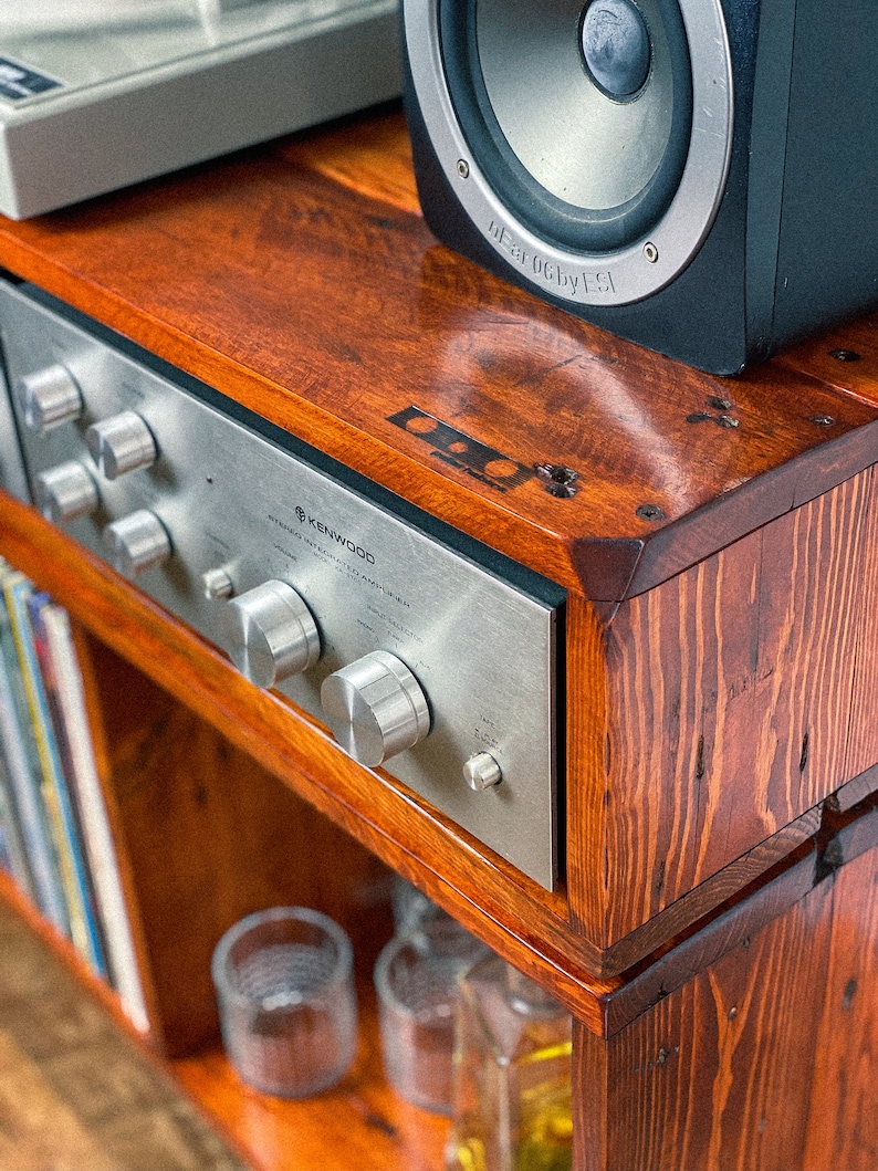 May include: A wooden shelf unit with a vintage Kenwood stereo receiver, a turntable, and a black speaker. The shelf has a dark wood stain and is made of reclaimed wood.