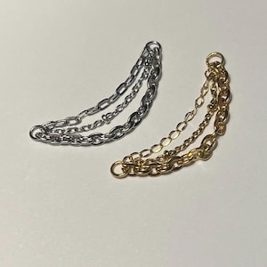 May include: Two multi-strand chain connectors, one in a silver-tone finish and one in a gold-tone finish. Each piece consists of three distinct chain lengths attached to a single circular jump ring at each end, creating a curved drape.