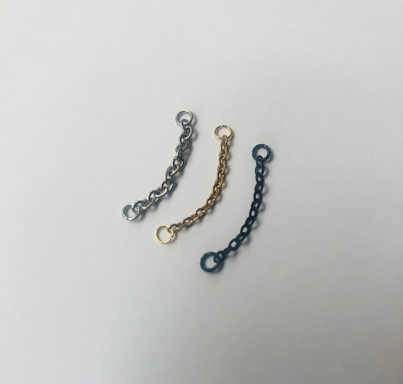 K&ouml;nnte beinhalten: Drei Kettenverl&auml;ngerungen in Silber, Gold und Schwarz. Jede Verl&auml;ngerung hat zwei Sprungringe an den Enden.