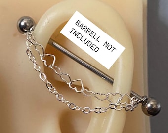 May include: Two silver chains with heart-shaped links dangle from a silver barbell piercing. The barbell is not included. The text "BARBELL NOT INCLUDED" is written on a white label.