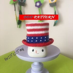May include: Crochet mug cozy in red, white, and blue colors, resembling the American flag. The cozy is designed to fit a 2.75 x 2.75 inch mug. PDF pattern included.