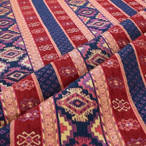 May include: Red, blue and pink striped fabric with a geometric pattern. The fabric has a woven texture and is ideal for upholstery or crafting projects.