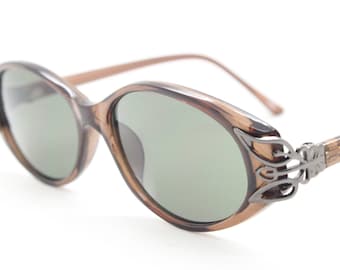 Lunettes de soleil oeil de chat ovales vintage des années 90. Monture oeil de chat discrète marron pour femme avec coins décoratifs en métal. Oeil de chat NSA inutilisé