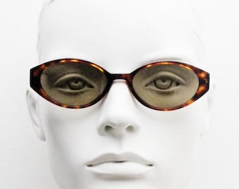 Vintage 90s oval cat eye sunglasses by Sunex. Minimalistic low profile tortoise quality acetate frame with cropped sides. Womens NOS.