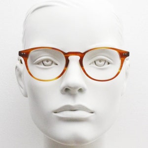May include: A white mannequin wearing round, tortoise-shell framed glasses.