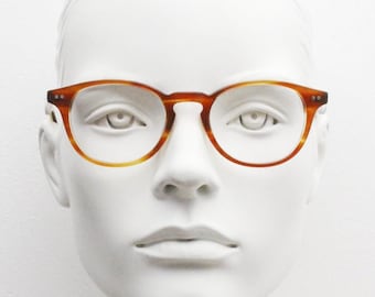 Puede incluir: Un maniquí blanco con gafas redondas de montura de carey.