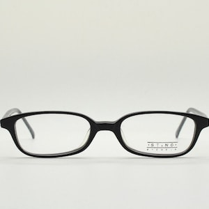May include: Black rectangular eyeglasses with clear lenses. The brand name "STING" is printed on the right temple.