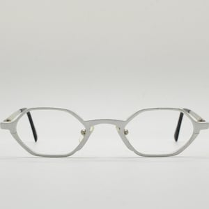 May include: Silver-toned metal eyeglasses with a geometric octagonal frame.