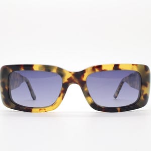 Gafas de sol rectangulares Komono modelo The Wes. Montura gruesa de acetato ecológico color carey miel con laterales traseros curvados tipo gafas y patillas largas.