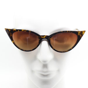 May include: Tortoise shell cat eye sunglasses with brown lenses. The sunglasses are on a white mannequin head.